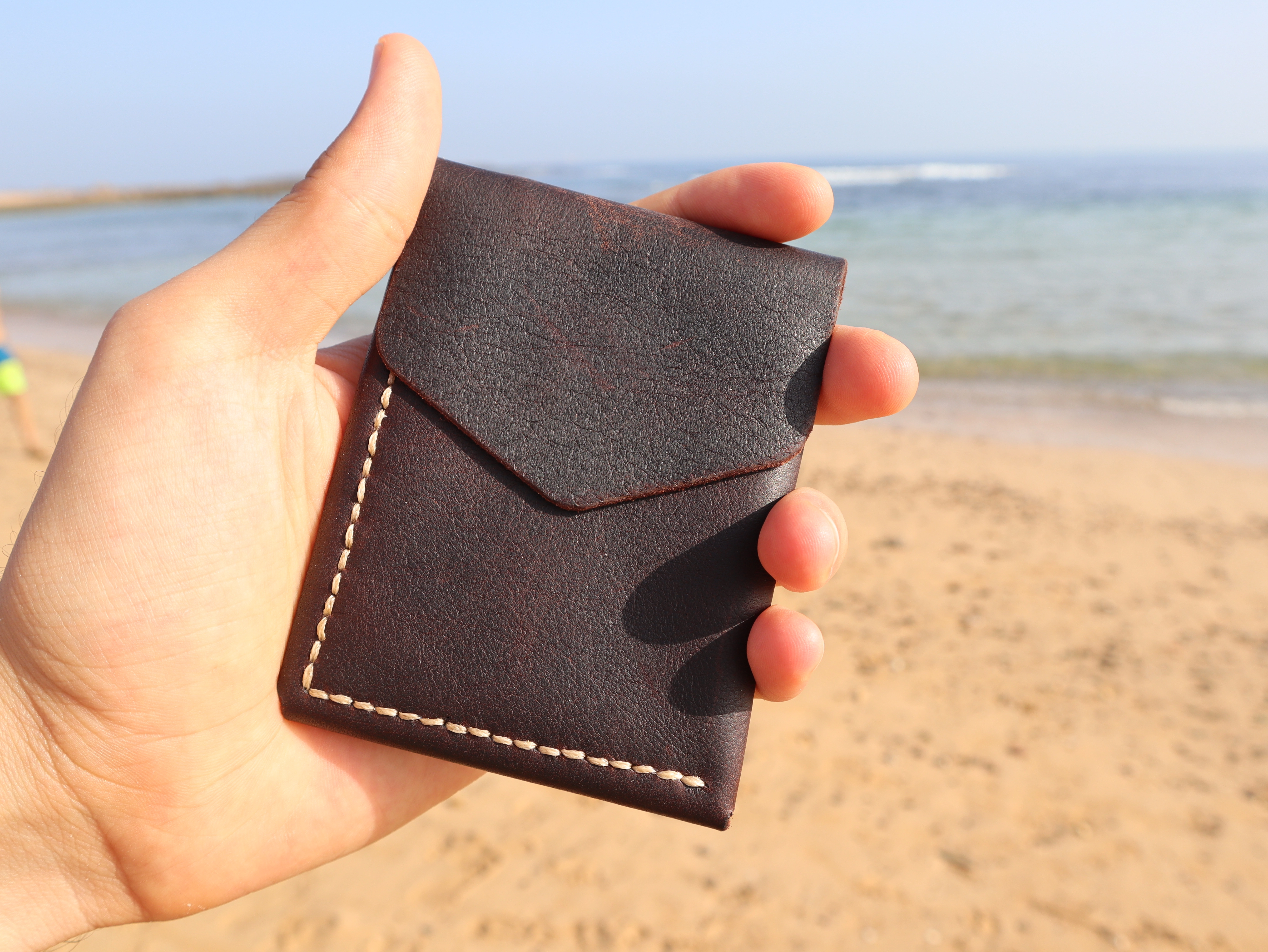 Porte-cartes Atlas en cuir Bordeaux avec couture beige, tenu en main
