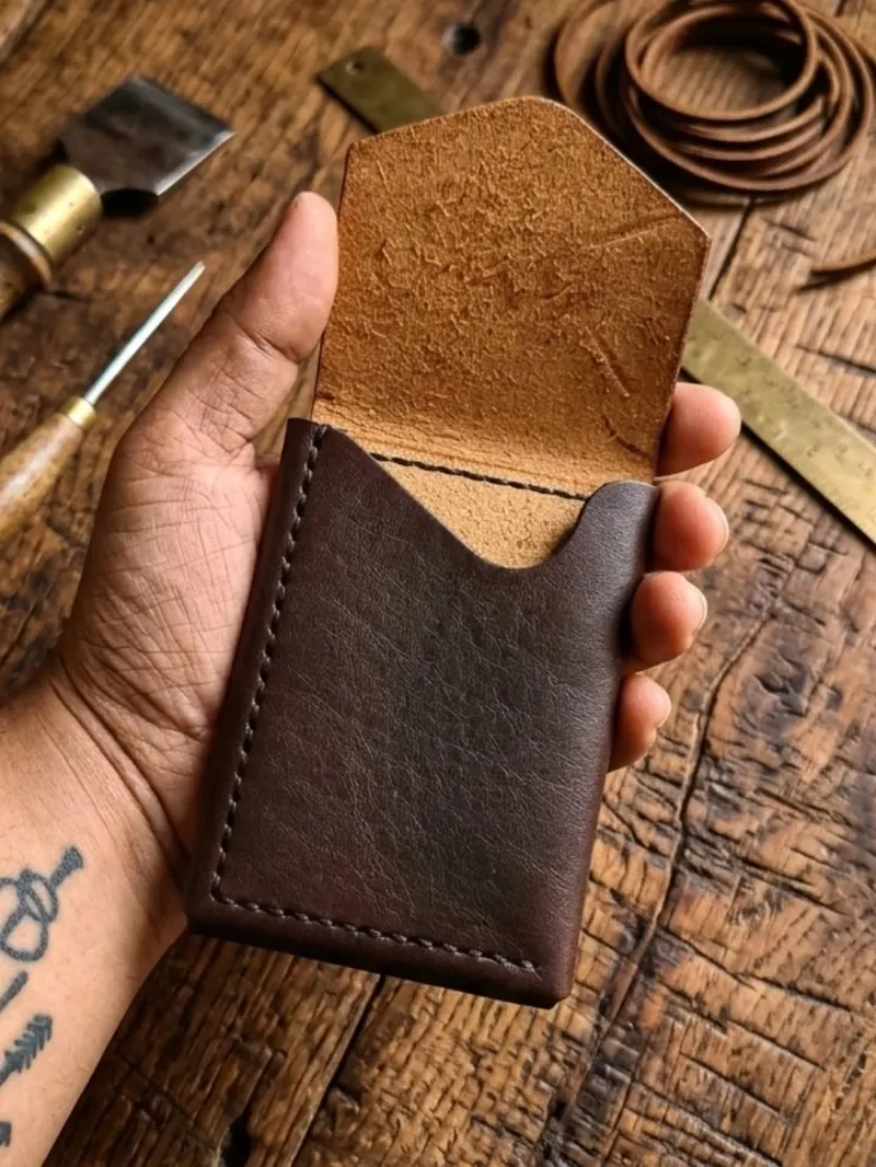 Porte-cartes Atlas en cuir espresso, ouvert, dans la main de l'artisan