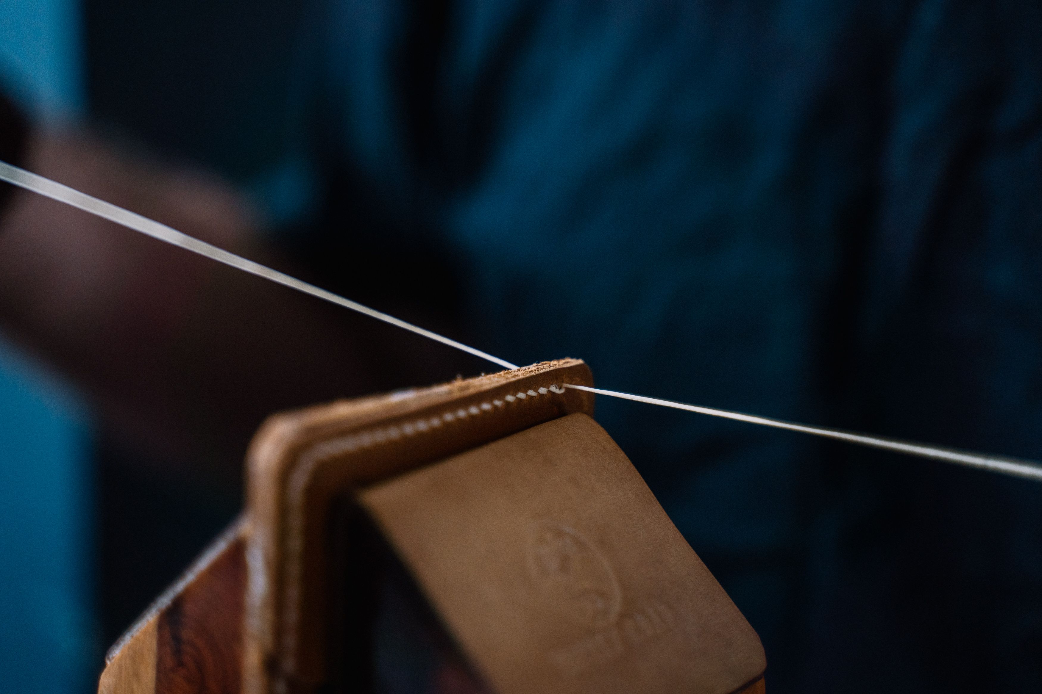 Détail de la couture sellier point par point sur un porte-cartes en cuir noir